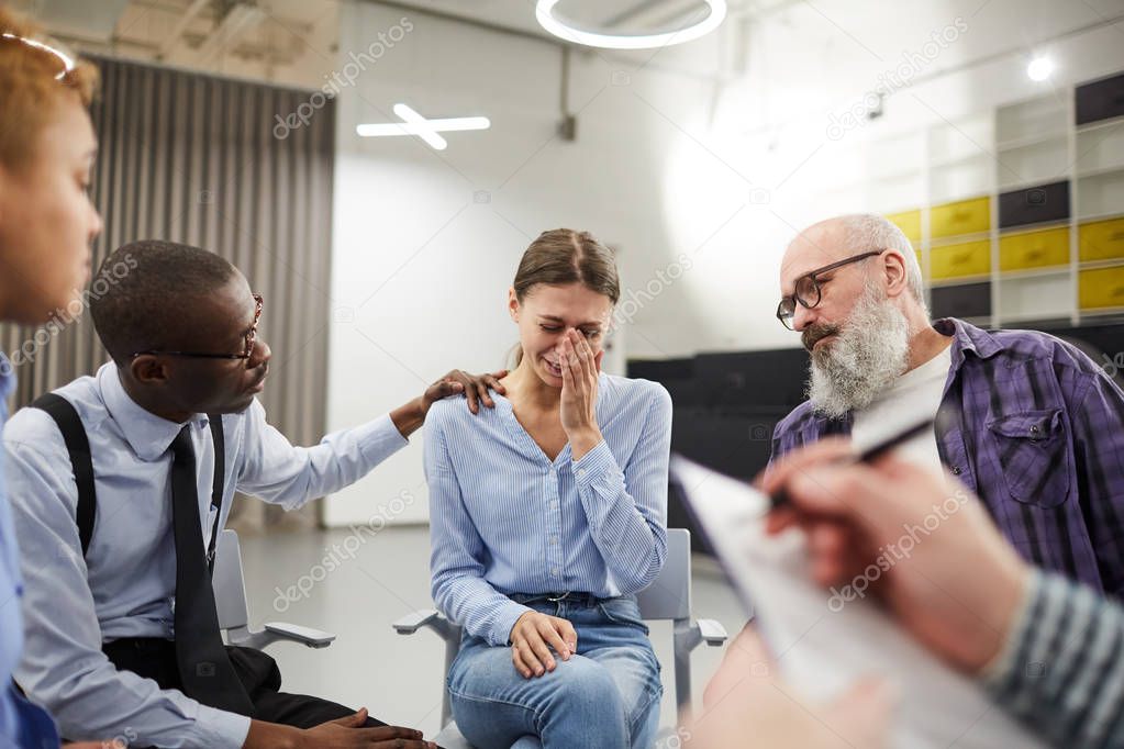 Portrait of young woman crying hysterically during therapy session in support group, copy space