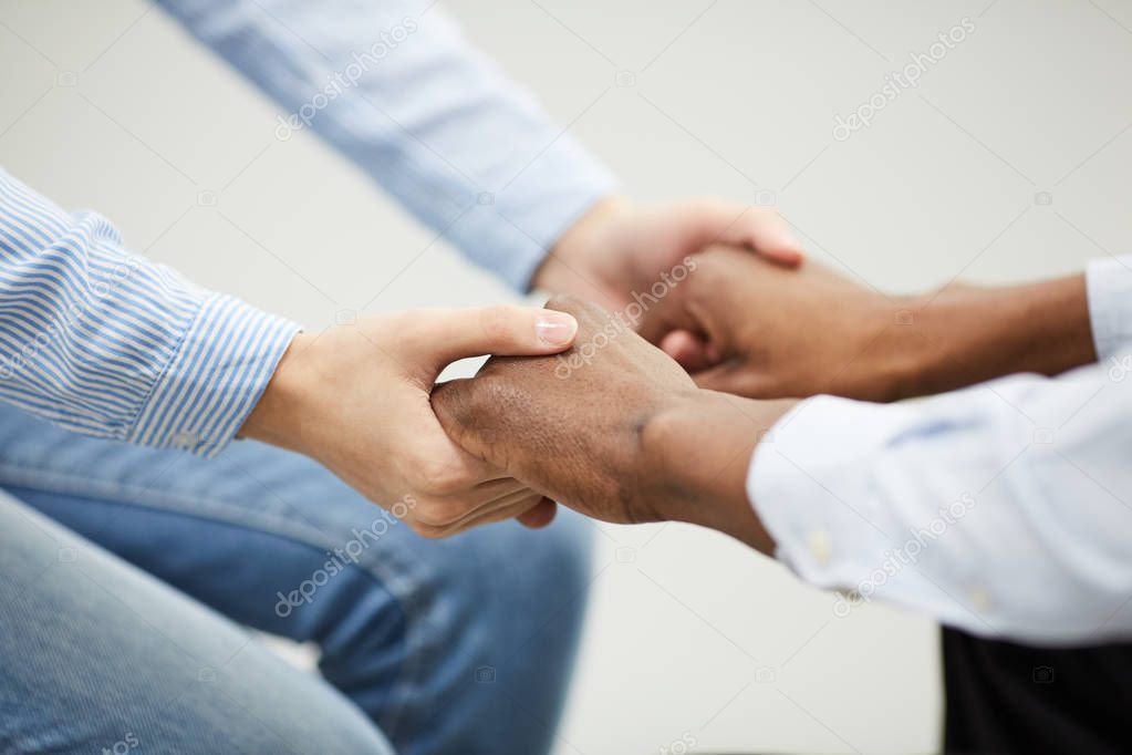 Closeup of two people holding hands heartily during therapy se4ssion in support group, copy space
