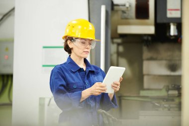 Fabrikada çalışan ve dijital tablet kullanan yetişkin kadının portresini belden yukarı ya, kopyalama alanı