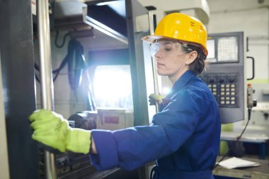 Üretim tesisinde makine üniteleri ile çalışan kadın mühendisin yan görünüm portresi, kopyalama alanı