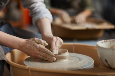 Döner çömlek tekerleğinde oturan ve atölyede ıslak yumuşak kil ile çalışan kirli elleri ile tanınmaz kadın yakın çekim