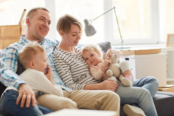 Glimlachende Dromerige Jonge Familie Casual Outfits Zittend Grote Bank Omhelzen — Stockfoto