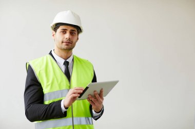 Beyaz arka plan tutan tablet karşı poz hardhat giyen Orta Doğu mühendisi bel kadar portre, kopya alanı