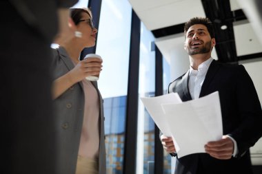 Onlar yeni bir strateji planlarken meslektaşları ile resmi ceket okuma raporu neşeli kendinden emin yakışıklı karışık ırk işadamı görünümü aşağıda