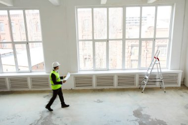 Şantiyede yürürken planları tutan tanınmayan mühendisin arka plan görüntüsü, kopya alanı