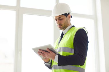 Pencere tutan tablet karşı duran hardhat giyen Orta Doğu mühendisi bel kadar portre, kopya alanı