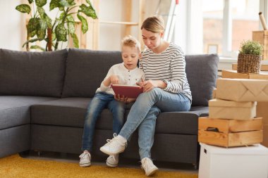 Oturma odasında kanepede oturan ve Online Kurs birlikte okurken tablette mobil uygulama kullanarak ciddi Genç Anne ve oğlu