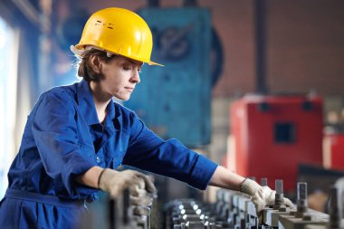 Industril fabrikasında çalışan genç kadının yan görünüm portresi parlak ışığa karşı ayakta, kopya alanı