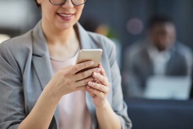 Mesaj veya sörf net mesajlaşma sırasında akıllı telefon kullanarak doğal manikür ile gülümseyen iş kadını yakın çekim