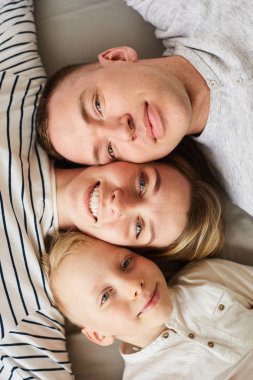 Birbirlerine benzeyen gülümseyen güzel genç ailenin hemen üstünde, birlikte yatarken ve kameraya bakıyor