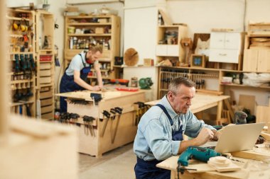 Atölyede masalarda duran ahşap ile çalışan iki marangozun yüksek açılı portresi, kopya alanı