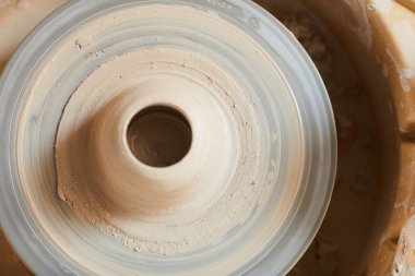 Seramik stüdyosunda kirli seramik tekerleği üzerine yerleştirilen orta delikli ıslak yumuşak kilin hemen üstünde