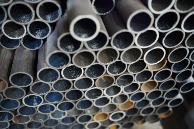 Endüstriyel tesisin deposunda yığılmış metal boruların arka plan görüntüsü, kopyalama alanı