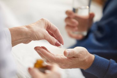 Yatakta yatan ve bakım karısı veya hemşire ile hap alarak tanınmayan yaşlı adam yakın, kopya alanı