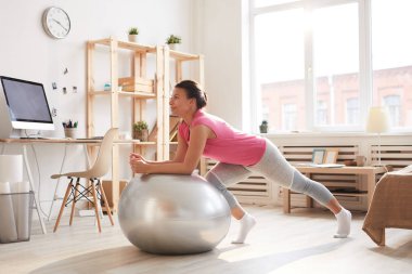 Güneş ışığında ev egzersiz sırasında fitness topu üzerinde egzersiz güzel karışık Yarış kadın tam uzunlukta portre, kopya alanı