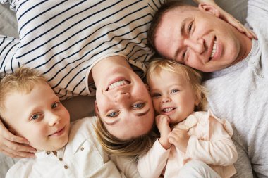 Mutlu pozitif güzel genç ailenin yüksek açı görünümü birlikte yalan ve kamera bakarak anne büyük kocası ve oğlu yüzleri