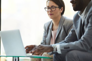 İçeriğin yakın çekim kahve masasında oturan ve dizüstü bilgisayar kullanarak resmi kıyafet li ırklar arası meslektaşları konsantre satış istatistikleri analiz ederken