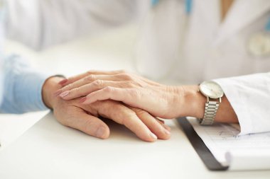 Konsültasyon sırasında hastaları el ele tutan kadın doktorun yakınçekimi, kopyalama alanı