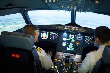 Düzlemde uçan sırada koltuklarda oturan ve uçak pozisyonunu tartışmak çizgili üniforma ile modern pilotların arka görünümü