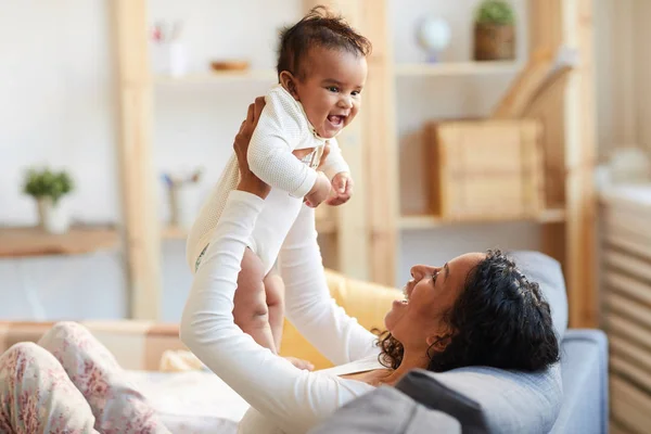 Feliz Joven Madre Africana Emocionada Sentada Sofá Criando Bebé Juguetón —  Fotos de Stock