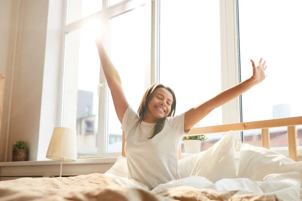 Retrato Una Hermosa Mujer Raza Mixta Estirándose Sentada Cama Iluminada —  Fotos de Stock