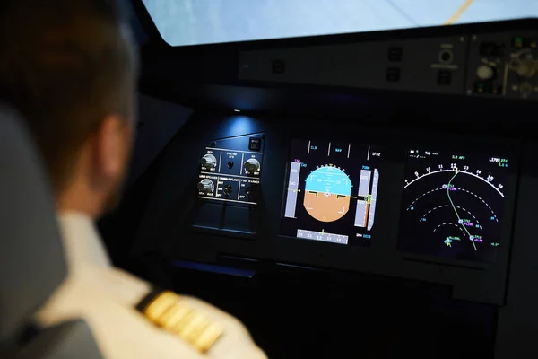 Over shoulder view of pilot sitting at aircraft dashboard with radar meters and planning flight route