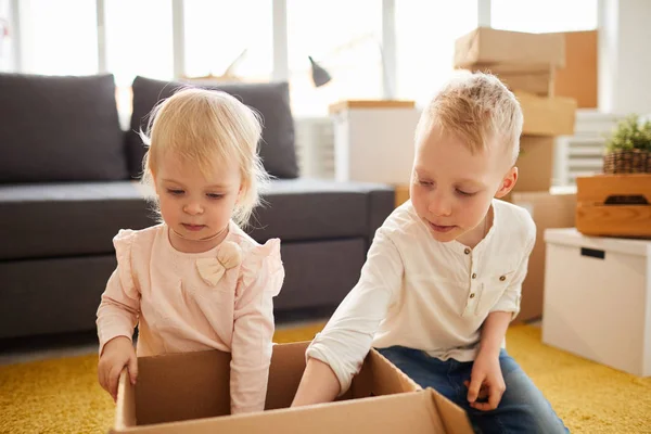 Serious Curious Brother Sister Sitting Floor New Home Fining Things — Stock Photo, Image