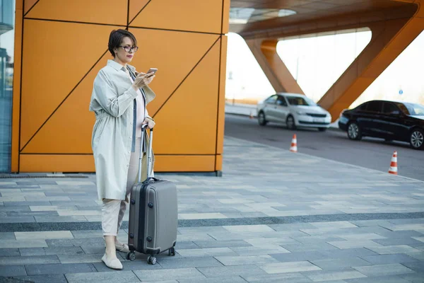 Havaalanı Bölgesinde Taksi Beklerken Tekerlekli Bagaj Kolu Akıllı Telefon Kullanarak — Stok fotoğraf