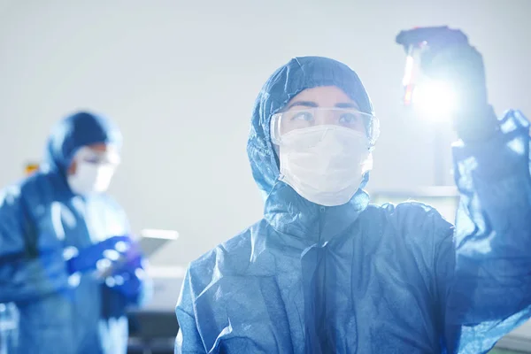 身着蓝色生物危害套装和安全护目镜的严重沉思亚洲病毒学家站在科学实验室 研究血液中的抗体 — 图库照片