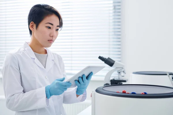 원심분리기에 실험실 코트에 심각한 집중된 아시아 연구원 타블렛에 시험의 — 스톡 사진
