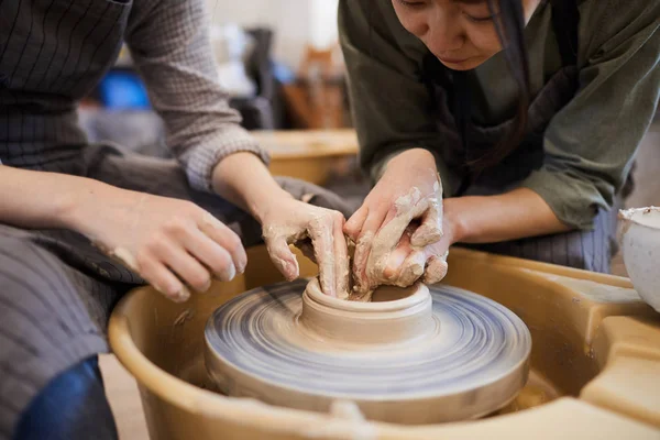 워크숍에서 도자기 바퀴를 사용하여 접시를 성형하는 방법을 여성에게 보여주는 아시아 — 스톡 사진