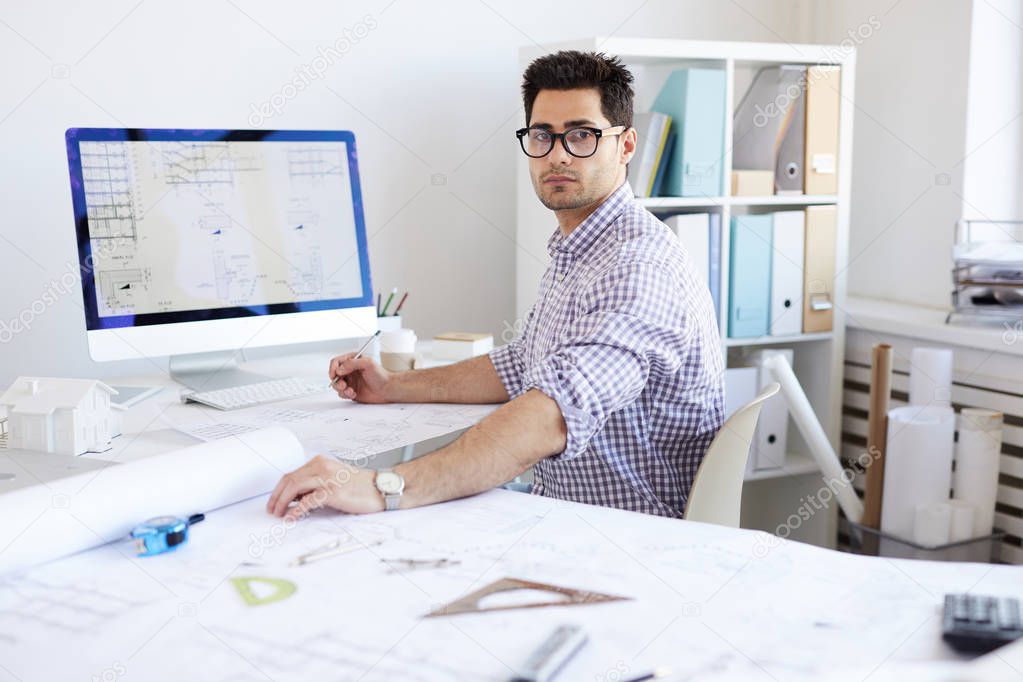 Portrait of contemporary engineer looking at camera while drawing digital plans in office, copy space