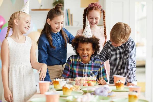 케이크에 얼굴을 당기는 아프리카 미국인 소년과 테이블에 생일을 축하하는 아이들의 — 스톡 사진