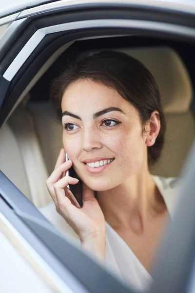 Portrait of smiling businesswoman using smartphone in taxi and looking at window