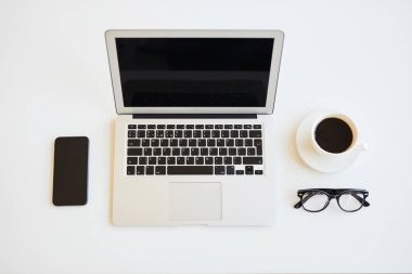 Açık dizüstü bilgisayar, bir fincan siyah kahve, gözlük ve akıllı telefon, siyah beyaz renkler ile minimalist serbest masanın doğrudan yukarıda görünümü