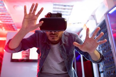 Veritabanı depolama odasında sanal gerçeklik simülatörü kullanırken ciddi meraklı genç orta doğu yenilik bilim adamı gesturing eller