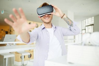 Renkli dövmeli neşeli meraklı hipster adam Vr kulaklık ayarlarken kameraya el uzanan sanal dünyaya dalmış