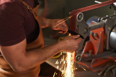 Demirci bıçak keskinleştirmek için bıçak taşlama jig kullanarak önlük tanınamayan esnaf yakın çekim