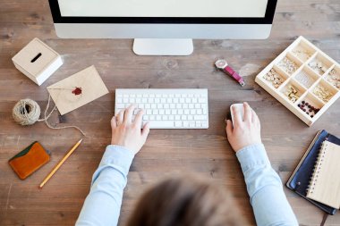 Web projesi üzerinde çalışırken aksesuarları ile masada oturan ve bilgisayar kullanarak gömlek tanınmaz grafik tasarımcı yüksek açı görünümü