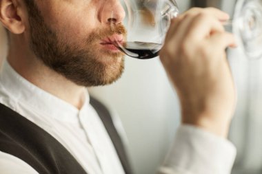 Restoranda tatma oturumu sırasında şarap içen yakışıklı sakallı adam Aşırı closeup, kopya alanı