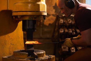 Metalurjik pres makinesi ile çalışırken Kulak koruyucuları ve emniyet gözlükleri ısıtmalı metal pres altında koyarak konsantre kel demirci