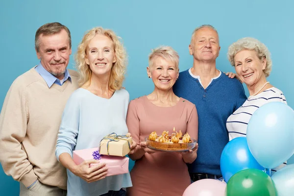 欢快的成熟朋友聚会生日派对的女士拿着甜蛋糕 他们一起摆出蓝色背景 — 图库照片