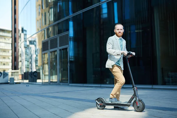 积极活跃男子与胡子骑推滑板车的肖像 而上下班后通勤回家 — 图库照片