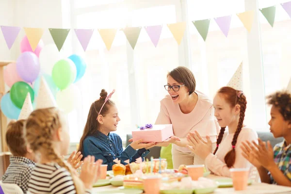 Portrait of excited little girl  receiving gifts during Birthday party with friends, copy space