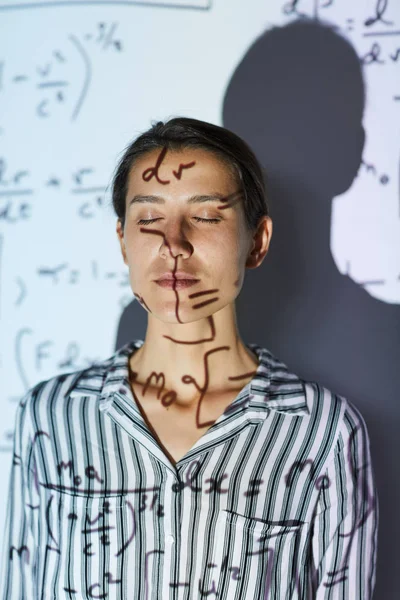 严肃冷静的年轻女数学家在剥离衬衫站在投影机的光和保持眼睛闭合 数学计算投影屏幕上 — 图库照片