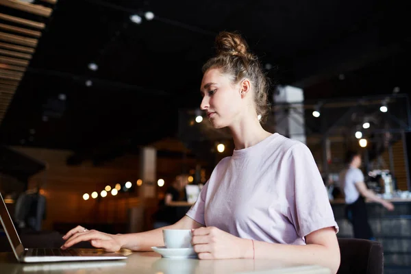 노트북을 사용하는 카페에서 테이블에 커피를 마시는 캐주얼 티셔츠에 심각한 프리랜서 — 스톡 사진