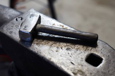 Yontulmuş yüzeyli çelik örs üzerine yerleştirilen ağır demircilerin yakın çekim iveznesi, arka plan görüntüsü