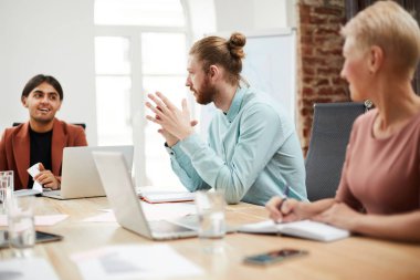 Ofiste toplantı masasında strateji tartışırken meslektaşlarıyla konuşurken çağdaş sakallı adamın yan görünüm portresi, kopya alanı