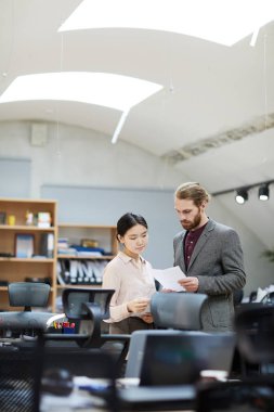 Yakışıklı işadamının ofiste dururken Asyalı sekreterle belge yi tartıştığı portresi, kopya alanı
