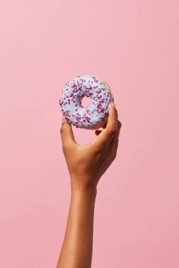 Closeup of unrecognizable African-American kid holding single glazed donut against pink background, copy space clipart